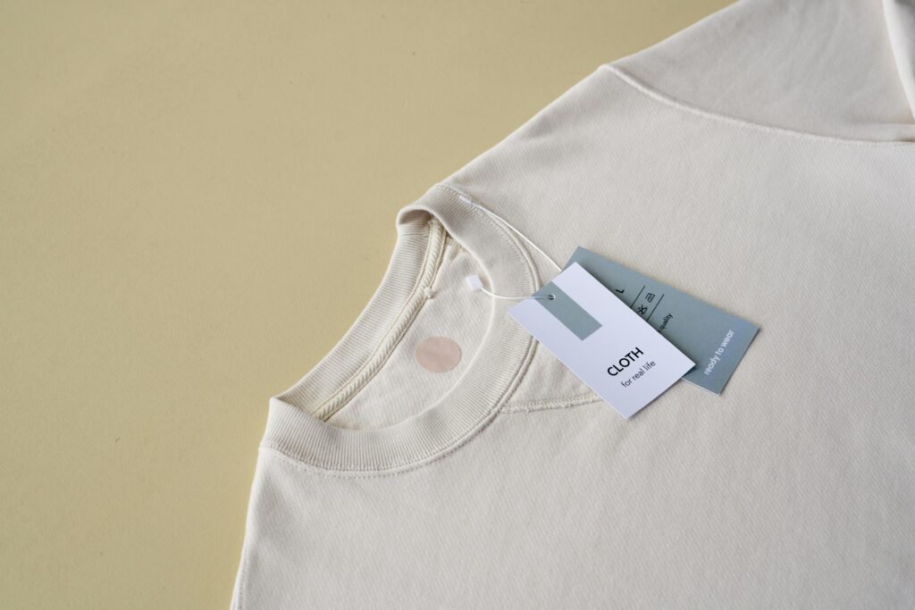 Minimalist beige sweatshirt displayed with tags on a yellow background, perfect for e-commerce.